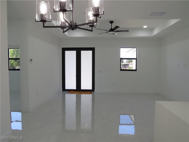 unfurnished room with a raised ceiling, tile patterned flooring, a notable chandelier, and french doors