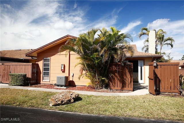 view of front facade with cooling unit and a front lawn