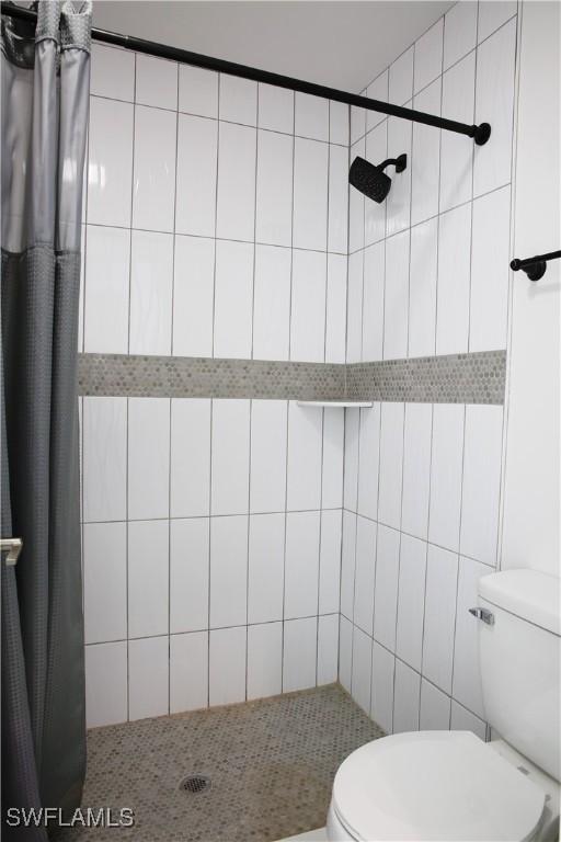 bathroom with toilet, a shower with shower curtain, and tile walls