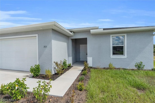 view of exterior entry featuring an attached garage and stucco siding