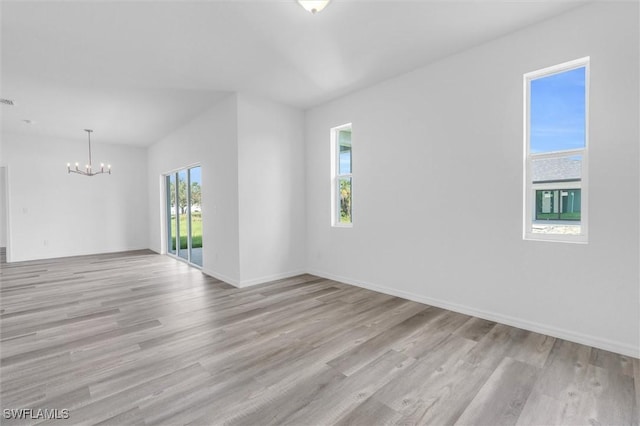 spare room with baseboards, a chandelier, and wood finished floors