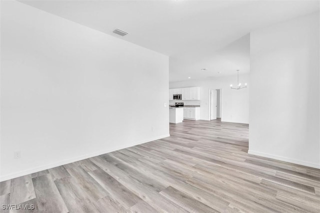 unfurnished living room with light wood-type flooring, baseboards, visible vents, and a notable chandelier