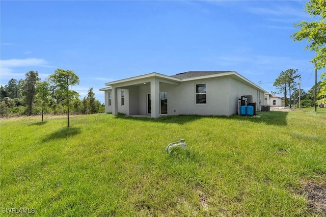 back of property with a yard and stucco siding