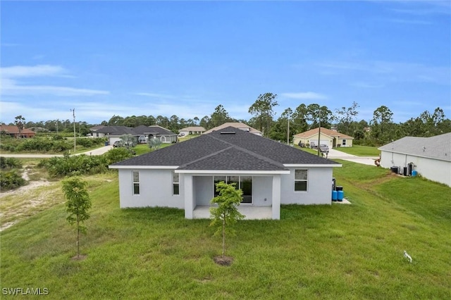 back of property with roof with shingles, a lawn, and stucco siding