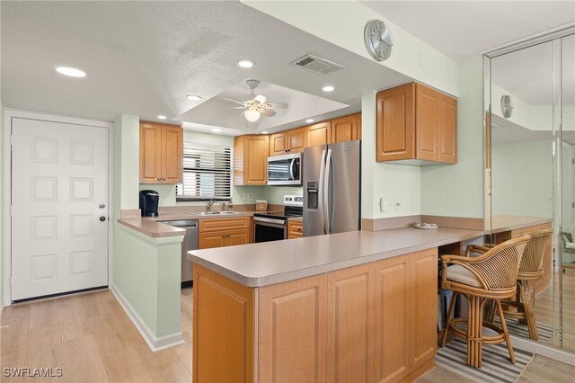 kitchen with ceiling fan, stainless steel appliances, kitchen peninsula, and sink