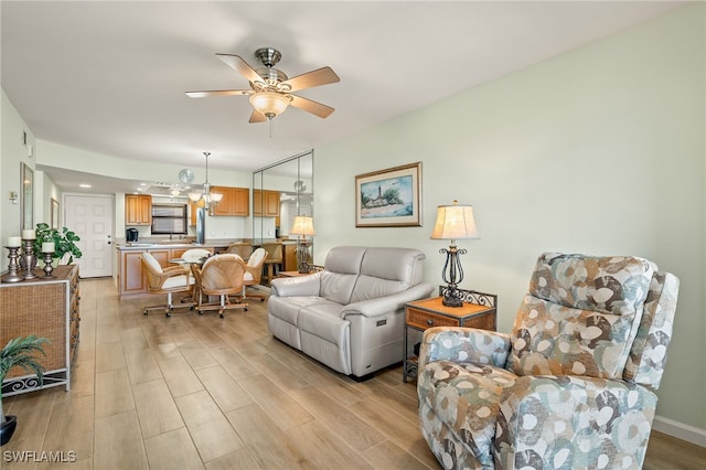 living room featuring sink, ceiling fan, and light wood-type flooring