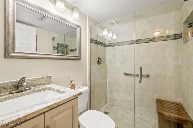 bathroom with a shower with door, vanity, and toilet