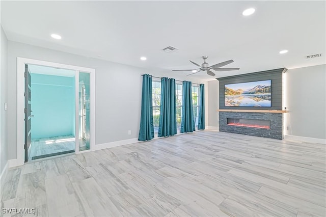 unfurnished living room with a stone fireplace and ceiling fan