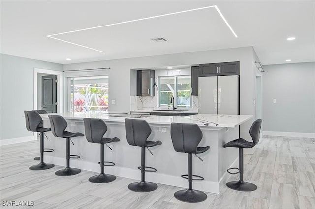 kitchen with sink, white refrigerator, a kitchen breakfast bar, a large island, and backsplash