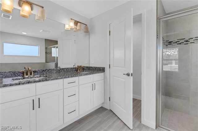 bathroom with vanity and a shower with door