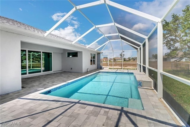 view of pool featuring glass enclosure and a patio area