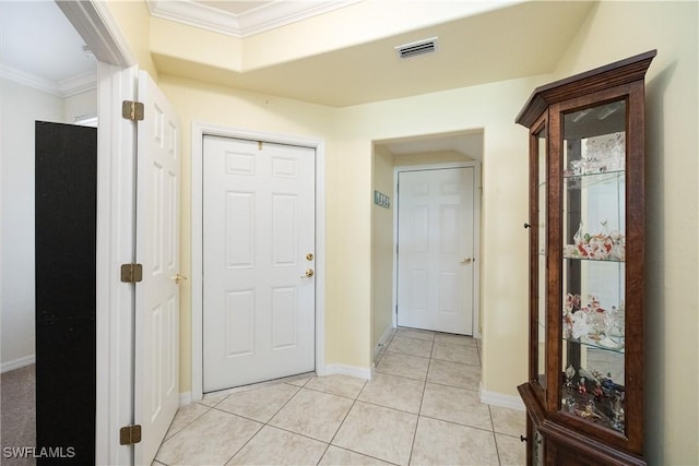 hall with ornamental molding, light tile patterned flooring, visible vents, and baseboards