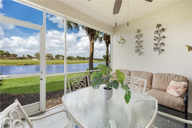 sunroom with a ceiling fan and a water view