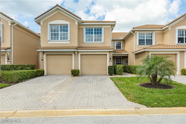 view of front of house with decorative driveway, an attached garage, a tile roof, and stucco siding