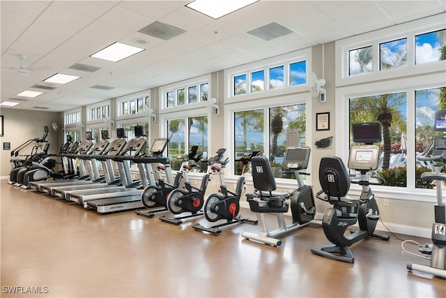 gym with a paneled ceiling and baseboards