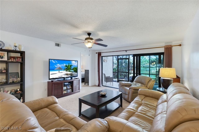 living room with ceiling fan, carpet floors, and a textured ceiling