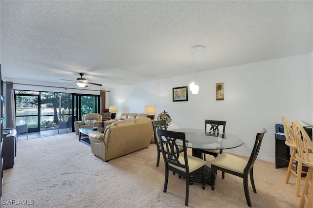 carpeted dining room featuring ceiling fan and a textured ceiling