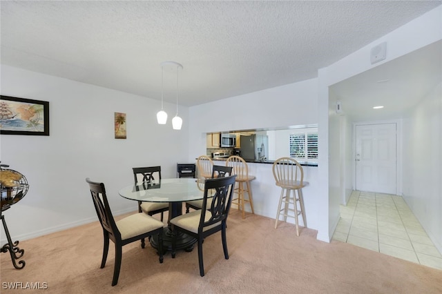 dining space featuring light colored carpet and a textured ceiling