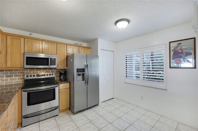 kitchen with light tile patterned floors, dark stone countertops, stainless steel appliances, tasteful backsplash, and a textured ceiling