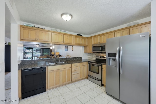 kitchen featuring appliances with stainless steel finishes, sink, dark stone countertops, backsplash, and kitchen peninsula