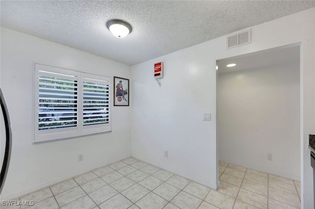 unfurnished room with light tile patterned floors and a textured ceiling