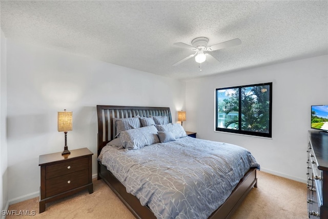 bedroom with ceiling fan, light carpet, and a textured ceiling