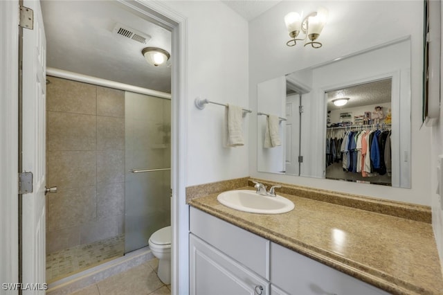 bathroom with tile patterned flooring, vanity, a shower with door, and toilet