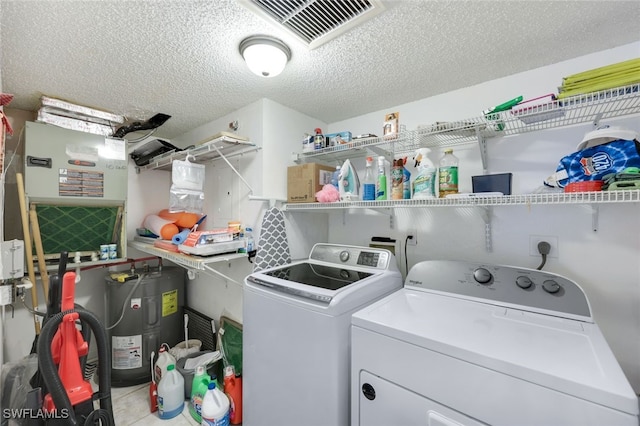 laundry room with water heater, independent washer and dryer, and a textured ceiling