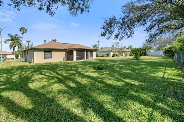 exterior space featuring stucco siding, fence, and a yard