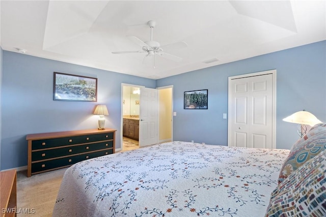 bedroom featuring ensuite bathroom, light colored carpet, ceiling fan, and a closet