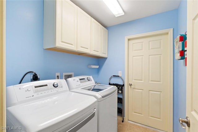 clothes washing area featuring cabinets, washing machine and dryer, and light tile patterned floors