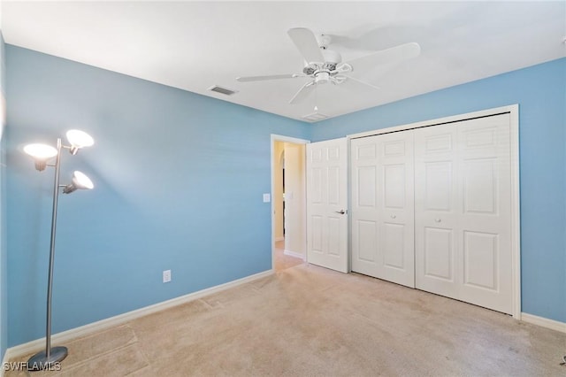 unfurnished bedroom featuring ceiling fan, light colored carpet, and a closet