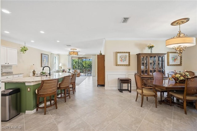 kitchen featuring white cabinetry, sink, a kitchen breakfast bar, hanging light fixtures, and light stone countertops