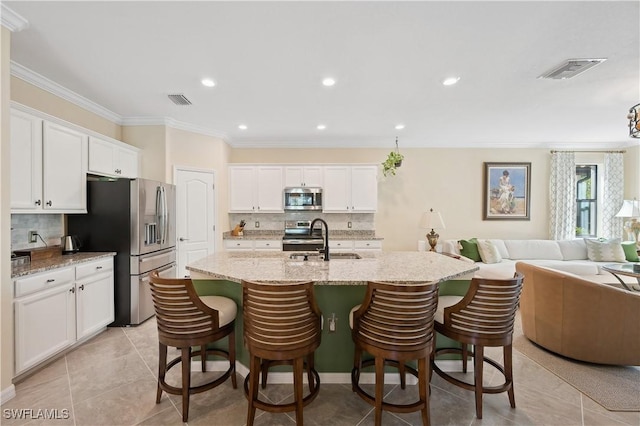 kitchen featuring stainless steel appliances, white cabinetry, sink, and a kitchen breakfast bar