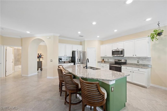 kitchen featuring a kitchen bar, sink, appliances with stainless steel finishes, an island with sink, and white cabinets