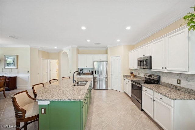 kitchen with an island with sink, appliances with stainless steel finishes, sink, and white cabinets