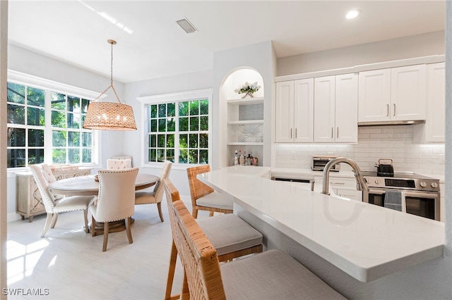 kitchen featuring white cabinetry, stainless steel electric range oven, decorative light fixtures, and tasteful backsplash