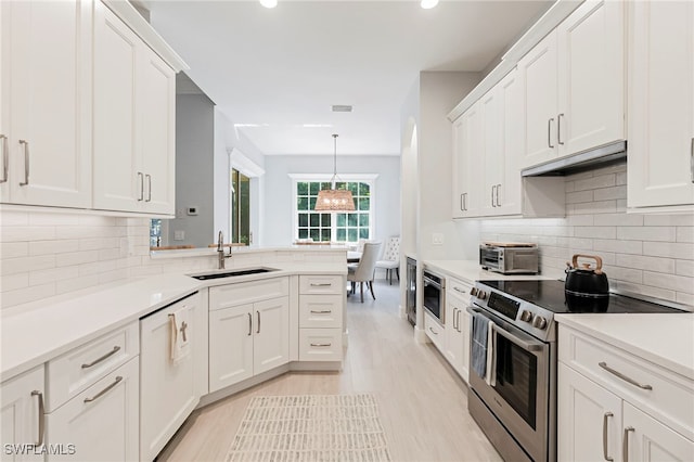 kitchen featuring sink, stainless steel range with electric stovetop, hanging light fixtures, decorative backsplash, and white cabinets