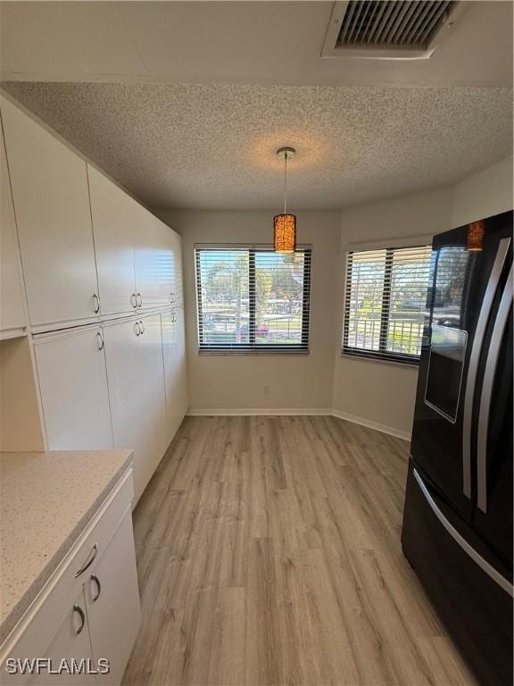 unfurnished dining area with light hardwood / wood-style flooring and a textured ceiling