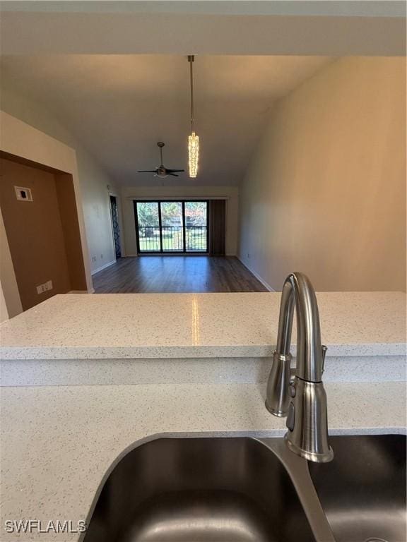 kitchen with dark hardwood / wood-style floors, decorative light fixtures, sink, ceiling fan, and light stone counters