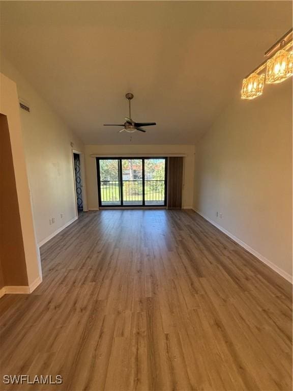 unfurnished living room featuring vaulted ceiling, ceiling fan with notable chandelier, and hardwood / wood-style floors