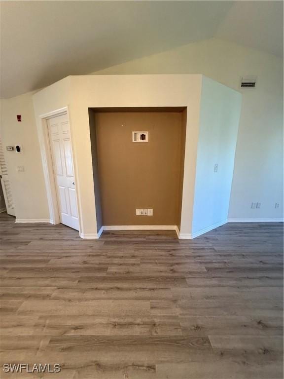 spare room featuring hardwood / wood-style flooring and vaulted ceiling