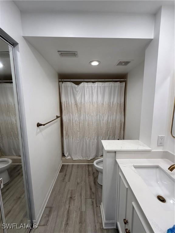 bathroom with hardwood / wood-style flooring, vanity, curtained shower, and toilet