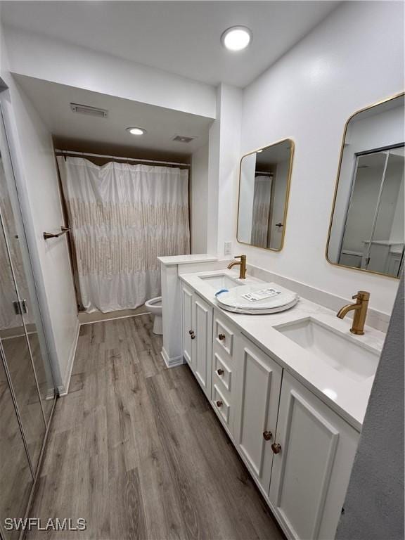 bathroom featuring vanity, hardwood / wood-style flooring, curtained shower, and toilet