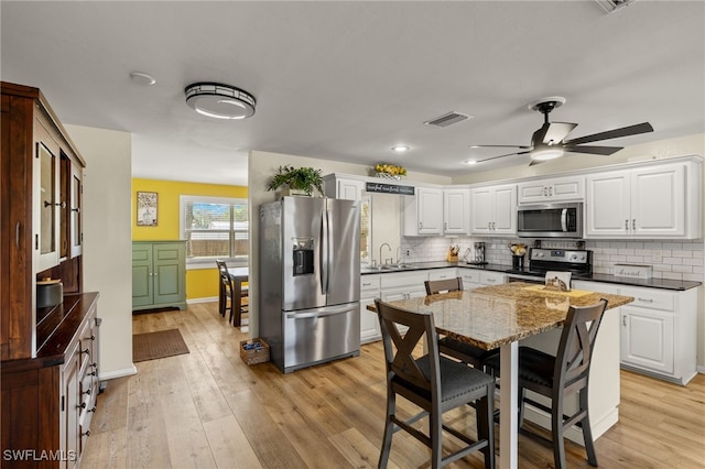 kitchen with appliances with stainless steel finishes, sink, white cabinets, and light hardwood / wood-style floors