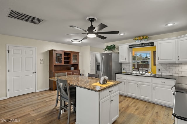 kitchen featuring white cabinetry, stainless steel fridge with ice dispenser, light hardwood / wood-style floors, and a center island