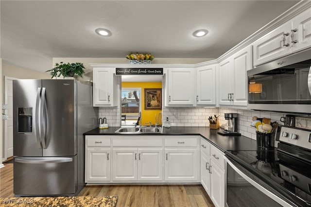 kitchen with appliances with stainless steel finishes, sink, white cabinets, and light hardwood / wood-style floors