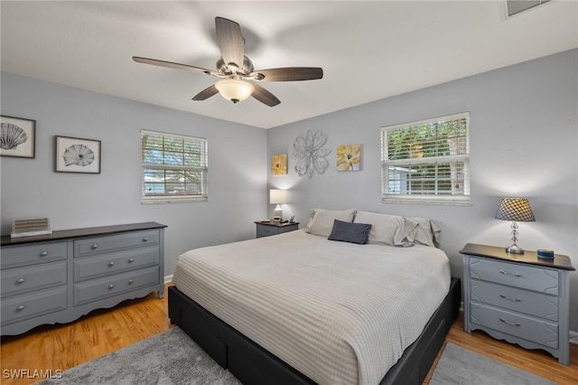 bedroom with ceiling fan, multiple windows, and light wood-type flooring