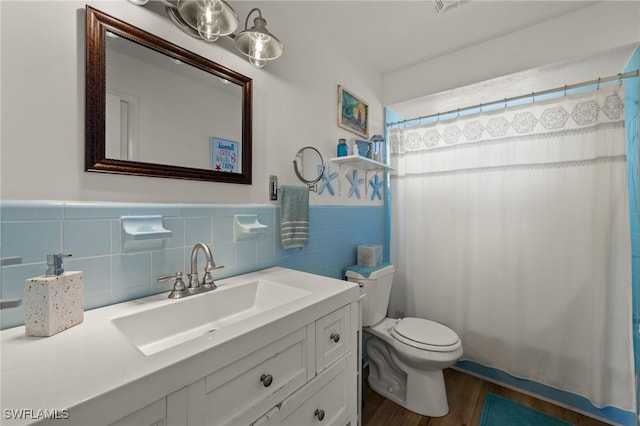 bathroom featuring curtained shower, wood-type flooring, tile walls, vanity, and toilet