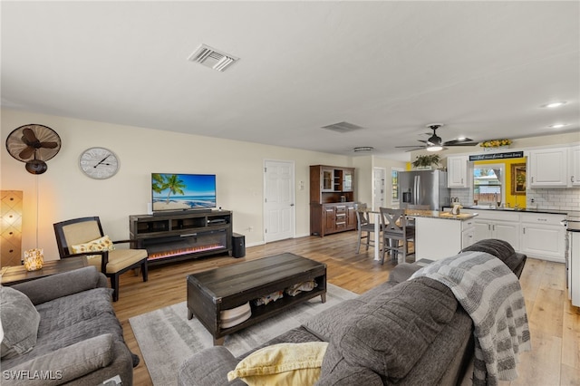 living room with light hardwood / wood-style flooring and ceiling fan